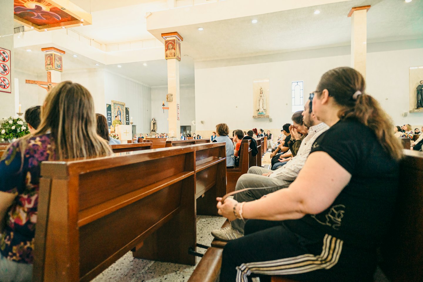 Congregation sits in wooden pews during a church service.