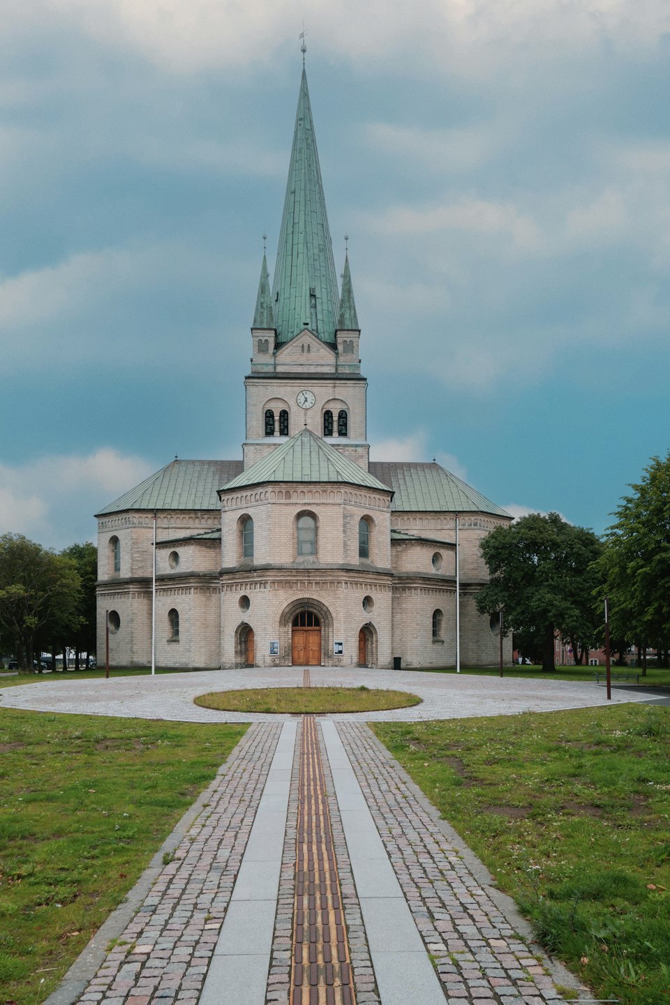 A stone church with green spires and a paved walkway.