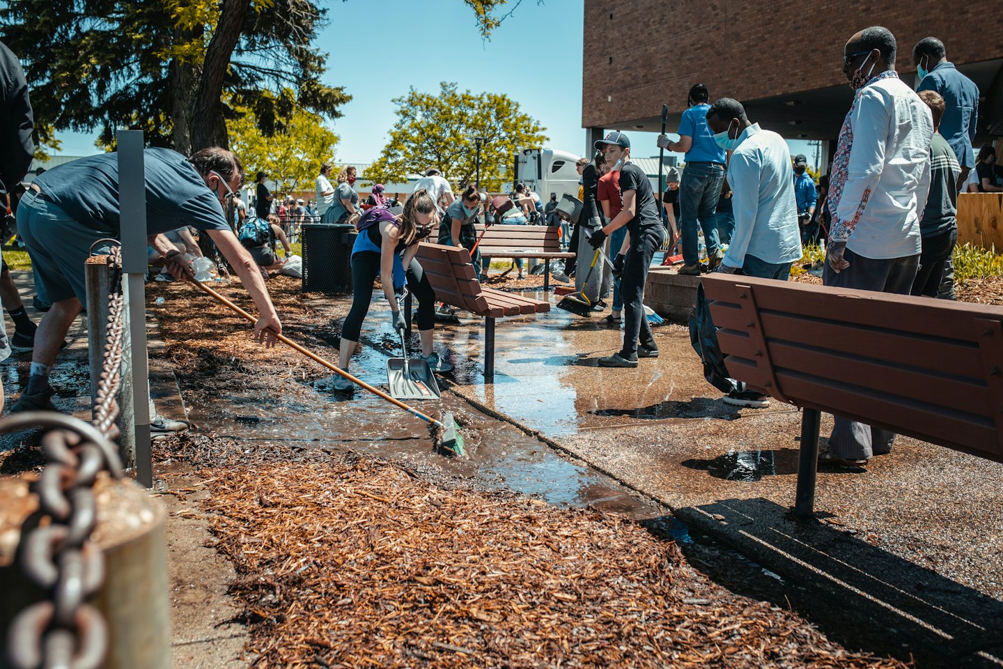 Volunteers clear wet debris from a paved area during a clean-up.